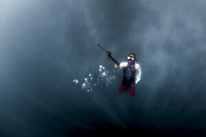 Malaysia, Boheyan island, 2024-05-10. Young Bajau man returning to surface after a freediving session looking for fish.