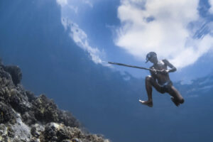 Malaysia, Mabul island, 2024-05-12. A Bajau laut freediver floating in the sea with his speargun. Photograph by Gilles A
