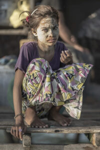 Malaysia, Boheyan island, 2024-05-10. A young Bajau Laut girl wearing a sun protection mask in front of their stilt hous