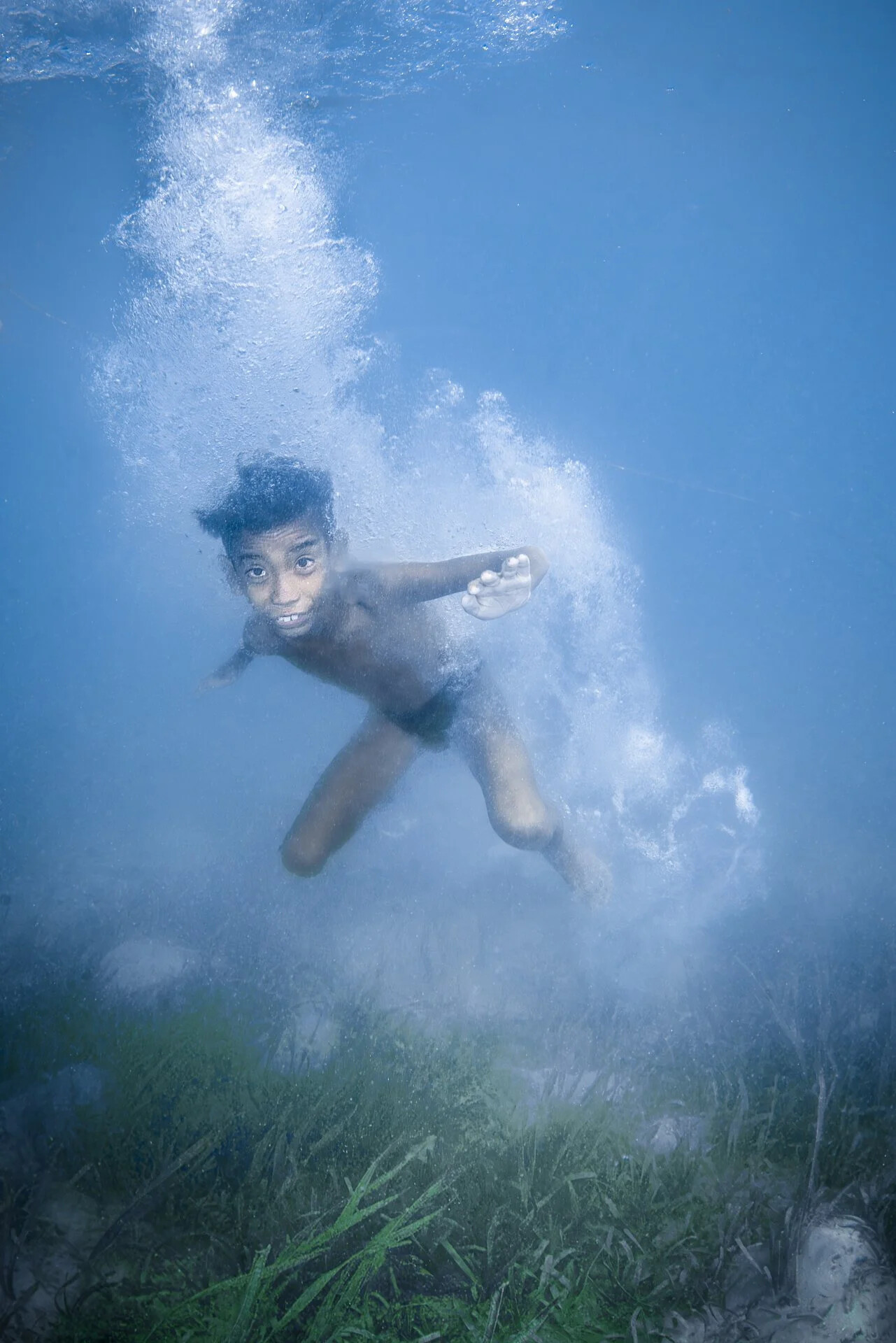 Malaysia, Omadal island, 2024-05-11. Young Bajau boy playing in the water and jumping from his stilt house. Photograph b