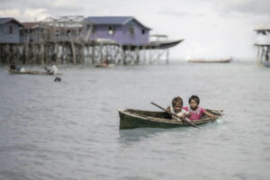 Malaysia, Denawan island, 2024-05-09. Bajau Laut children moving around in a canoe near their Bajau village. Photograph