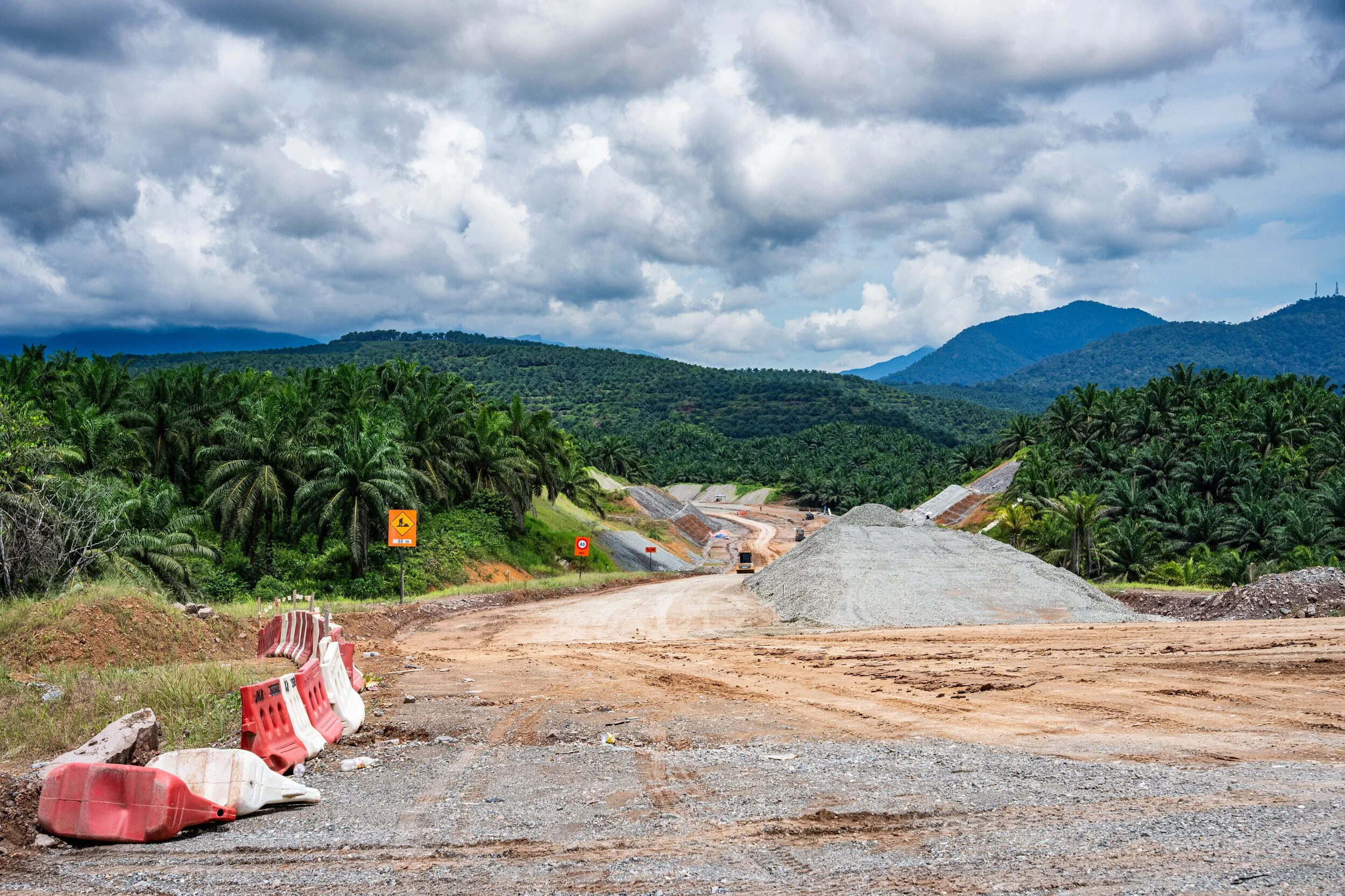 Malaysia, Telupid, 2026-06-10. Construction work of the pan Borneo highway through palm oil plantation and primary fores