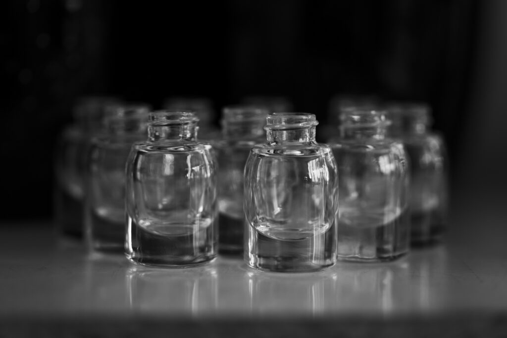 France, Blangy-sur-Bresle, 2022-03-24. Rows of empty glass bottles on a reflective surface, black and white. Photograph