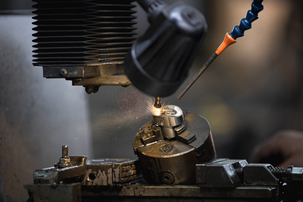 France, Bouttencourt, 2023-02-23. Close-up of a metal part being machined on a lathe, with the operator's gloved hand an