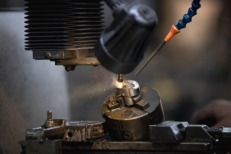 France, Bouttencourt, 2023-02-23. Close-up of a metal part being machined on a lathe, with the operator's gloved hand an