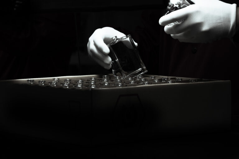 France, Guimerville, 2021-01-13. Gloved hands handle glass vials on a tray in a pharmaceutical laboratory, black and whi