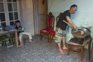 Indonesia, Tomohon, 2026-09-13. The brother of Ipam Daulima cooks dog meat in a wok to make RW for Pengucapan Syukur, wh