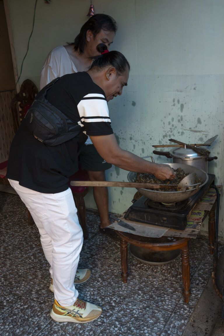 Indonesia, Tomohon, 2026-09-13. A guest tastes RW, dog meat cooked with Minahasa spices, straight from the wok on a gas 