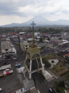 Indonesia, Tomohon, 2026-09-13. Aerial view of a alpha and omega tower with a bell tower and cross overlooking Tomohon c