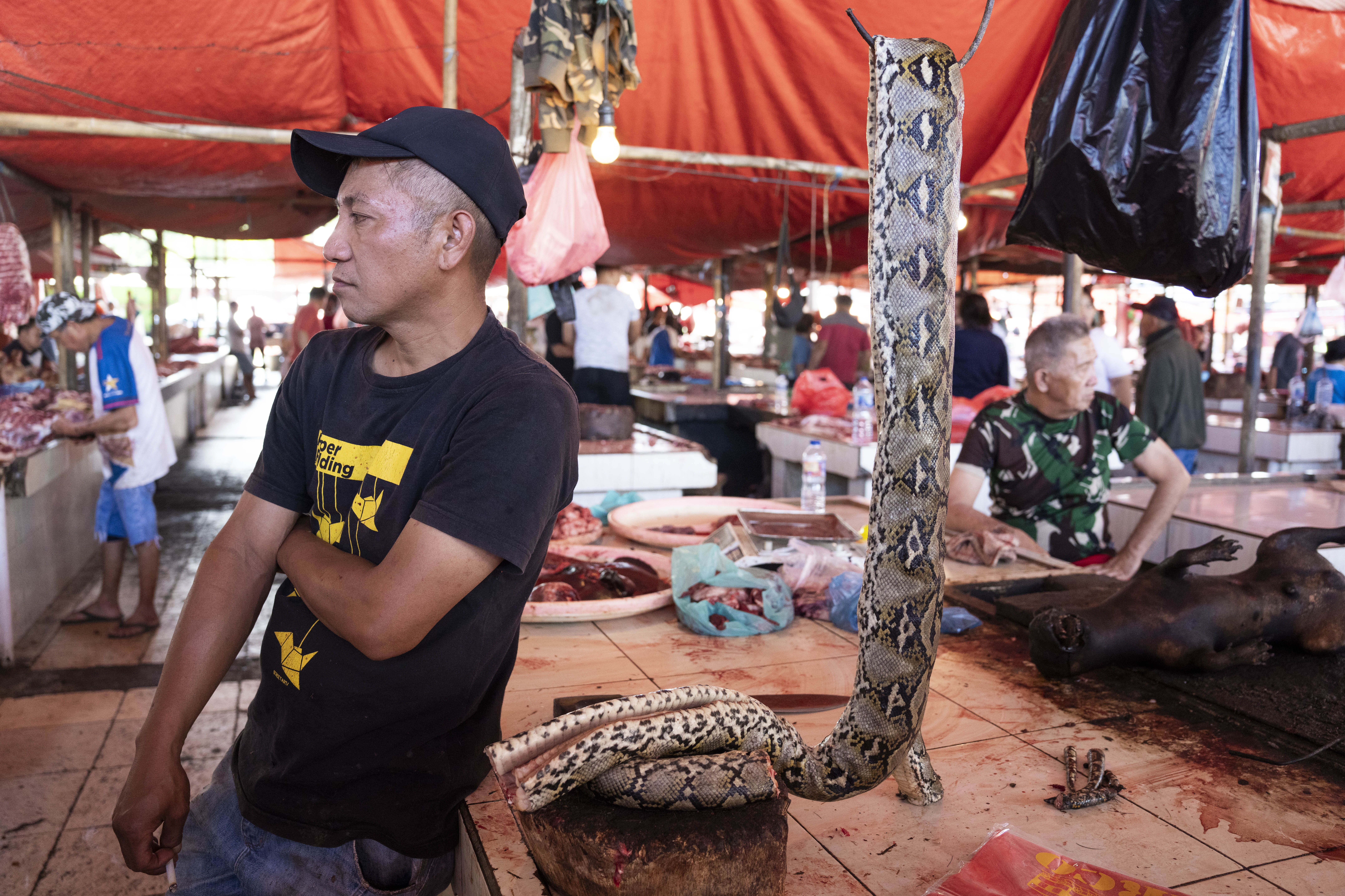 Indonesia, Tomohon, 2026-09-11. Yanes Romanka, meat vendor at Tomohon market, smoking a cigarette in front of his stal, 