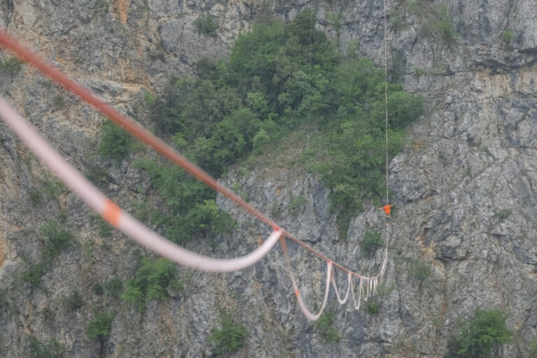 Croatia, Imotski, 2018-05-03. Above the Red Lake, a collapsed karst sinkhole near Imotski, a team rigs highlines and jum