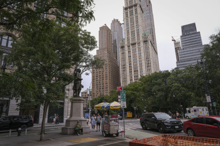 United States, New York, 2026-08-16. A statue and food carts at the edge of City Hall Park in front of the Woolworth Bui