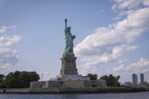 United States, New York, 2026-08-15. The Statue of Liberty on its island, with the skyline of Manhattan in the distance.