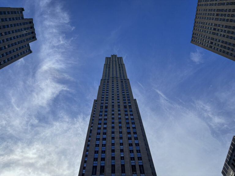 United States, New York, 2026-08-17. The tower of 30 Rockefeller Plaza seen from below between two buildings. Photograph