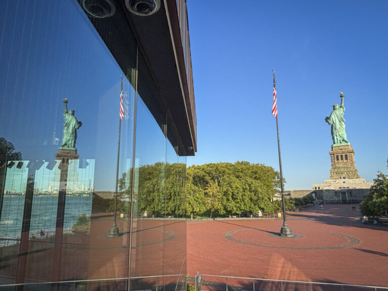 United States, New York, 2026-08-15. The Statue of Liberty and its reflection on the glass facade of the museum on Liber