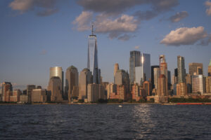 United States, New York, 2026-08-15. The skyline of Lower Manhattan lit by the setting sun, reflected on the glass of a
