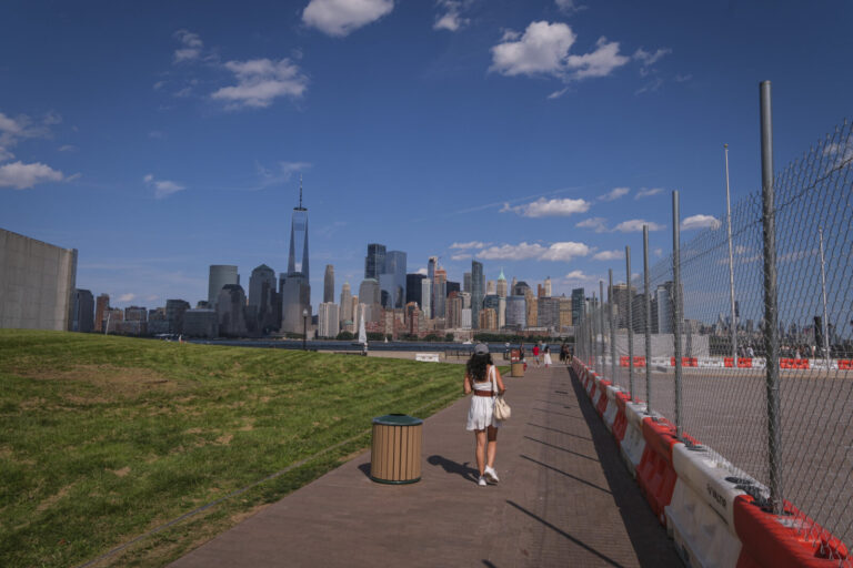 United States, Jersey City, 2026-08-15. A woman walks along the promenade of Liberty State Park, facing the skyline of M