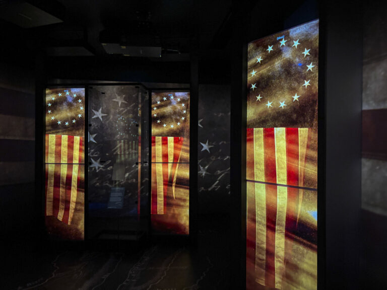 United States, Washington, 2026-08-12. Projected American flags of the revolutionary period around a display case. Photo