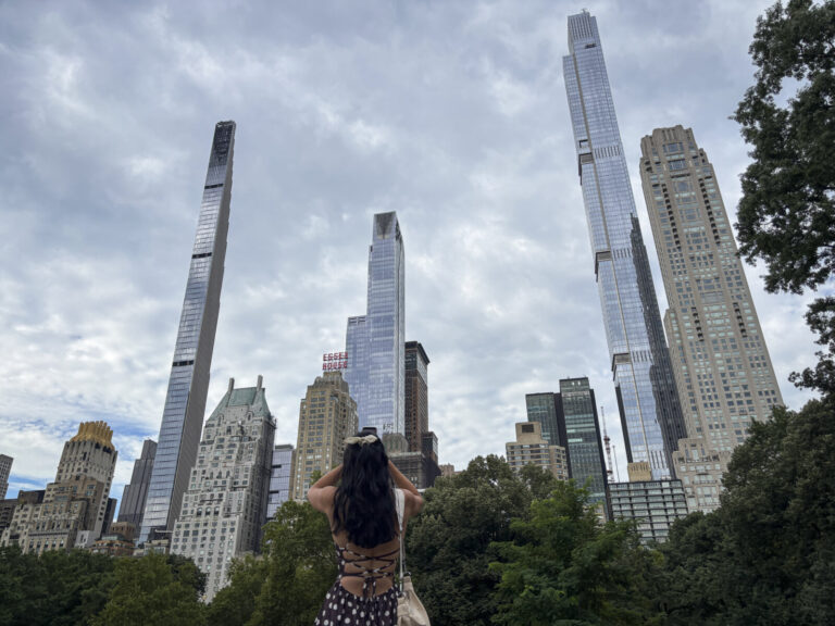 United States, New York, 2026-08-05. A visitor photographs the towers of Central Park South from the rocks. Photograph b
