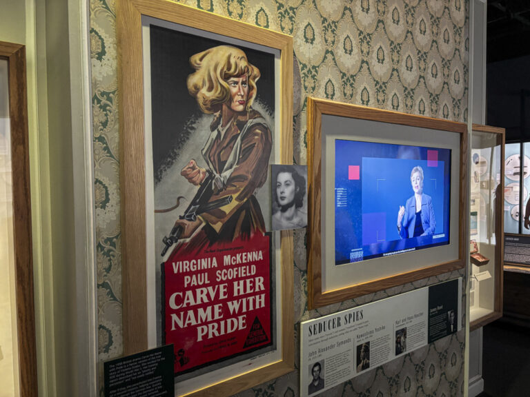 United States, Washington, 2026-08-12. A poster for the film Carve Her Name With Pride beside a panel on seducer spies. 