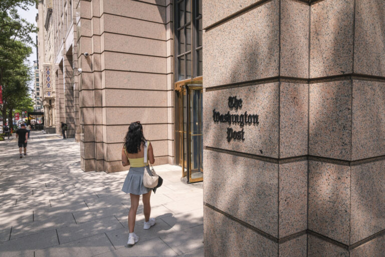 United States, Washington, 2026-08-11. A woman walks past the entrance of the Washington Post headquarters. Photograph b