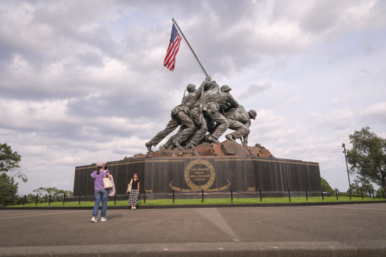 United States, Arlington, 2026-08-11. Two visitors photograph each other in front of the Marine Corps War Memorial and i