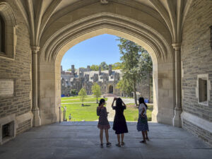 United States, Princeton, 2026-08-15. Three visitors under the archway of Blair Hall, looking out over the campus. Photo