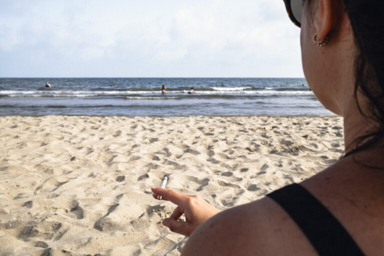 France, LA GRANDE MOTTE, 2026-08-03. France, Occitanie, La Grande-Motte, 3 aout 2026 : Femme fumant sur la plage. Un an 