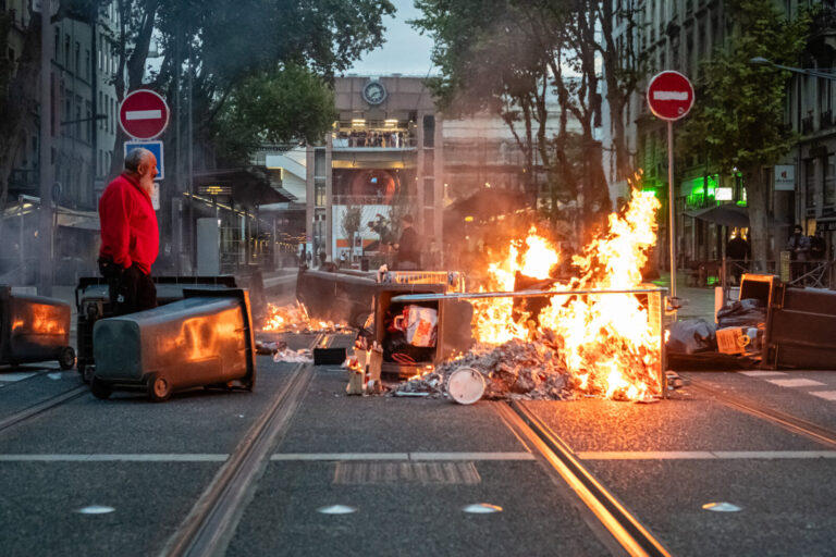 France, Lyon, 2025-09-10. A barricade of burning rubbish bins in front of Perrache station, with a man surveying the dam