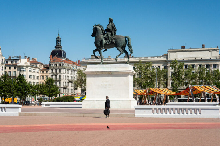 France, Lyon, 2026-04-23. Place Bellecour with its equestrian statue of King Louis XIV and a pedestrian walking past. Ph