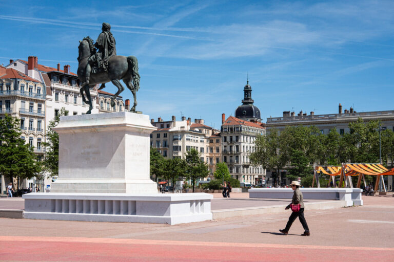 France, Lyon, 2026-04-27. Place Bellecour, featuring its equestrian statue of King Louis XIV and a pedestrian wearing a 