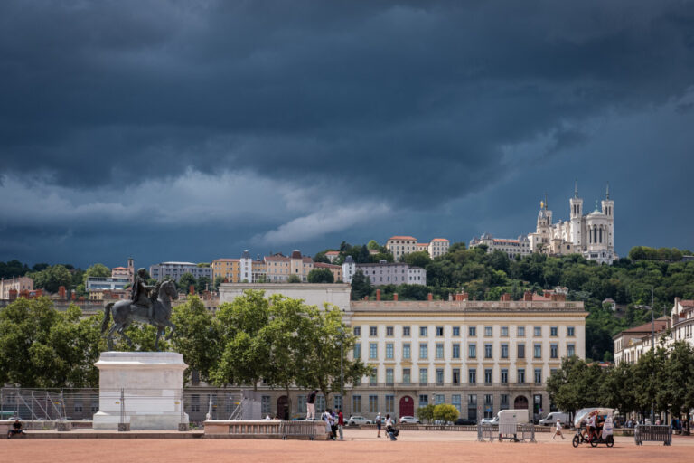 France, Lyon, 2024-07-12. View of the Fourviere basilica from Place Bellecour under a dark, stormy and cloudy sky. Photo