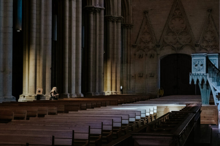 France, Lyon, 2023-03-16. Interior of the almost empty cathedral of St. Jean with a woman in the light between the pilla