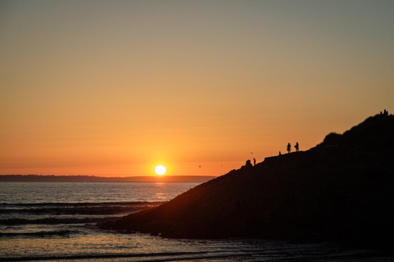 France, Plonevez Porzay, 2024-08-10. Sunset at the edge of the ocean with characters on a cliff which are detached from
