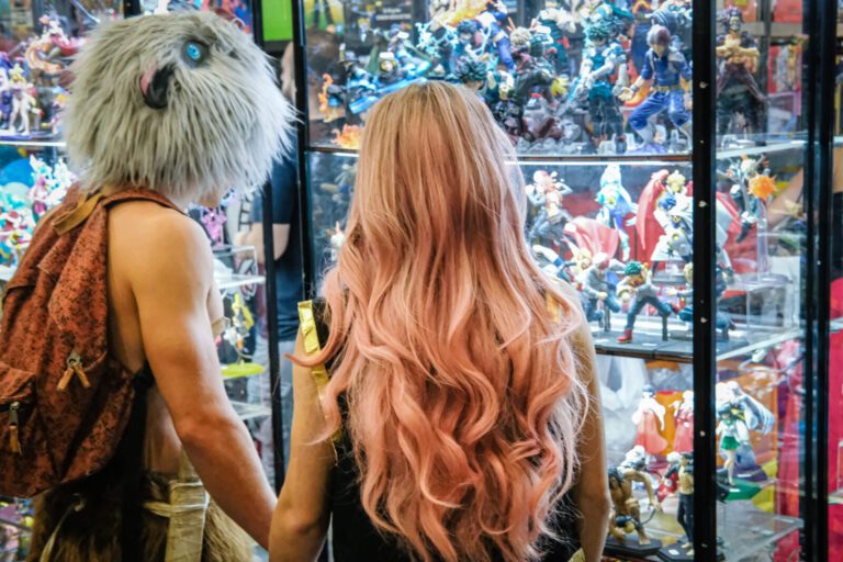 France, Lyon, 2022-11-13. Two people with their backs to the cosplay looking at figurines in a shop window. Photograph b