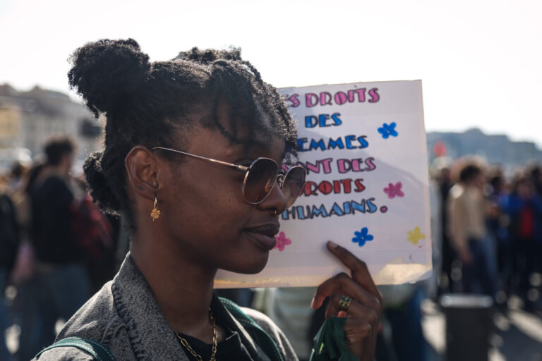 France, Marseille, 2025-03-08. March for the International Women's Day. Woman holding a protest sign. Photograph by Fran