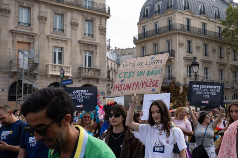 France, Paris, 2026-10-03. Marchers walk beneath signs reading 'Vieillir LGBTQ c'est un droit pas un privilege' (Growing