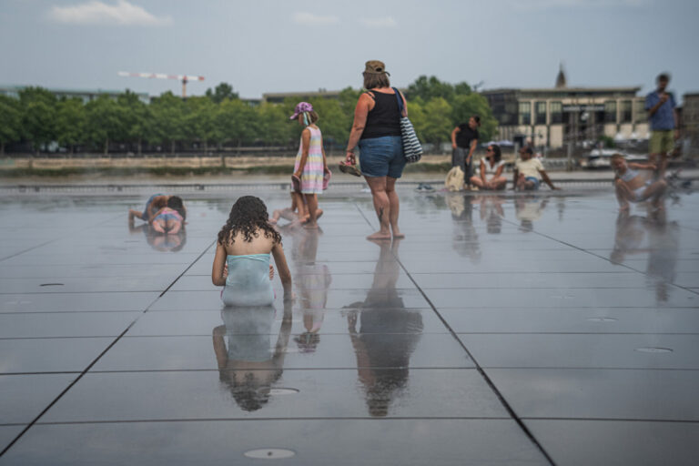 France, Bordeaux, 2026-07-13. Children playing in the reflecting pool in Bordeaux, trying to cool down during the summer