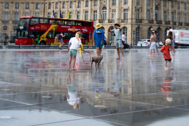 France, Bordeaux, 2026-07-13. A little girl walks her dog across Bordeaux's Mirror of Water, trying to cool off during t