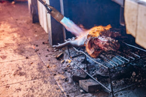Indonesia, Tomohon, 2026-09-12. Vendor singeing a small carcass on a grate in the heart of the busy Tomohon market. Phot