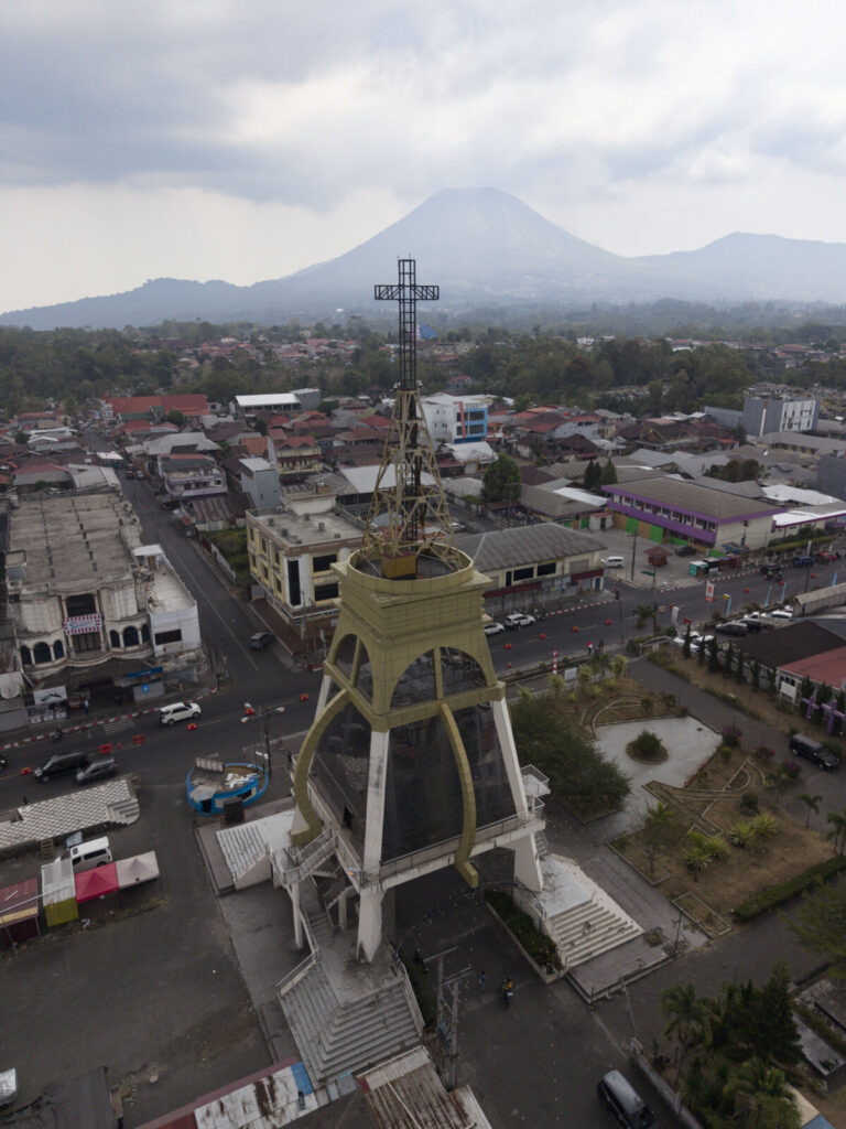 Indonesia, Tomohon, 2026-09-13. Aerial view of a alpha and omega tower with a bell tower and cross overlooking Tomohon c