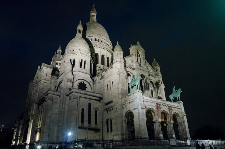France, Paris, 2015-11-30. The Sacre-Coeur Basilica, illuminated at night, overlooks the Montmartre Hill from the top of