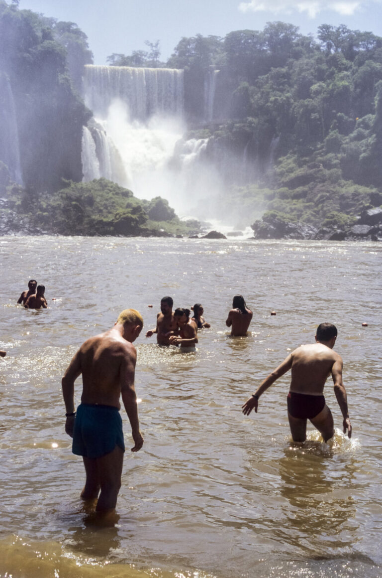 Argentine, Iguazu, 2005-01-20. Visitors swim on the beach of San Martin Island, in Iguazu National Park, with the waterf