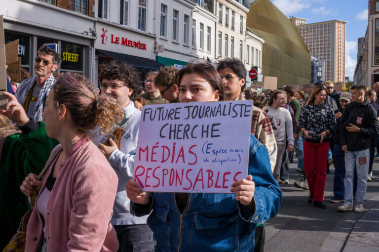 France, Lille, 2026-10-17. A protester in a denim jacket holds a sign calling for responsible media, surrounded by march