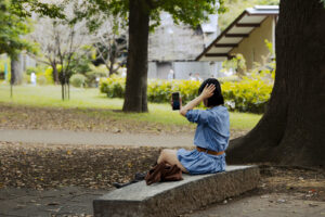 Japon, Tokyo, 2025-09-30. Japon, Tokyo, 2025-09-30, Zoo quartier Ueno, Une femme assise sur un banc en pierre prend une