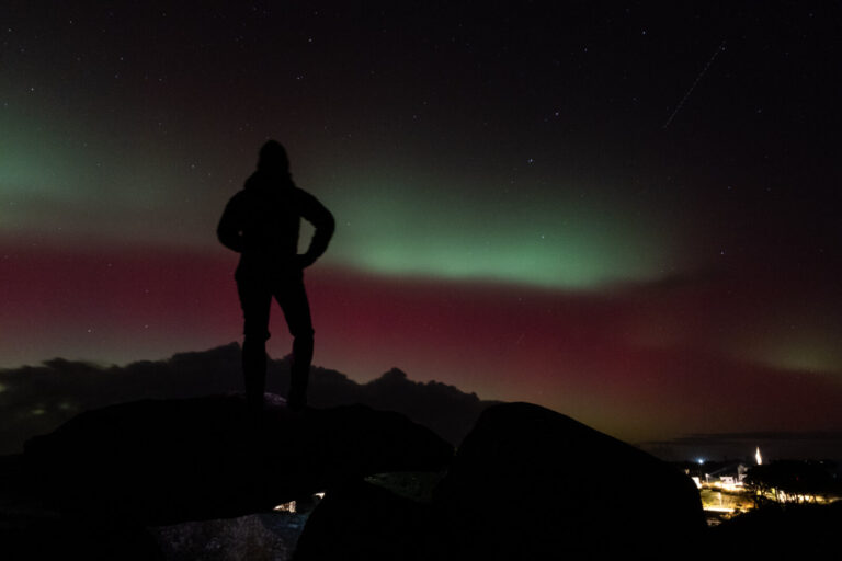 France, Portsall, 2026-01-19. - A women witnesses a rare sight : Auroras in the west coast of France ; following a power