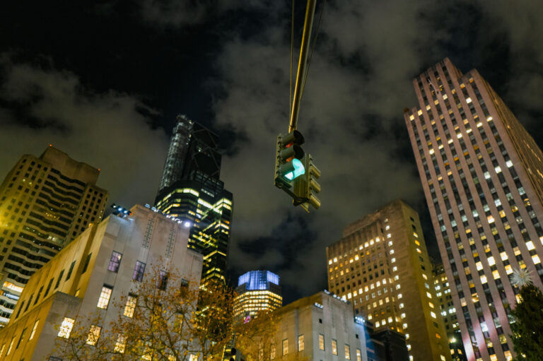 USA, New York, 2024-11-27. A traffic light displaying a green arrow signal hangs prominently in the foreground against a