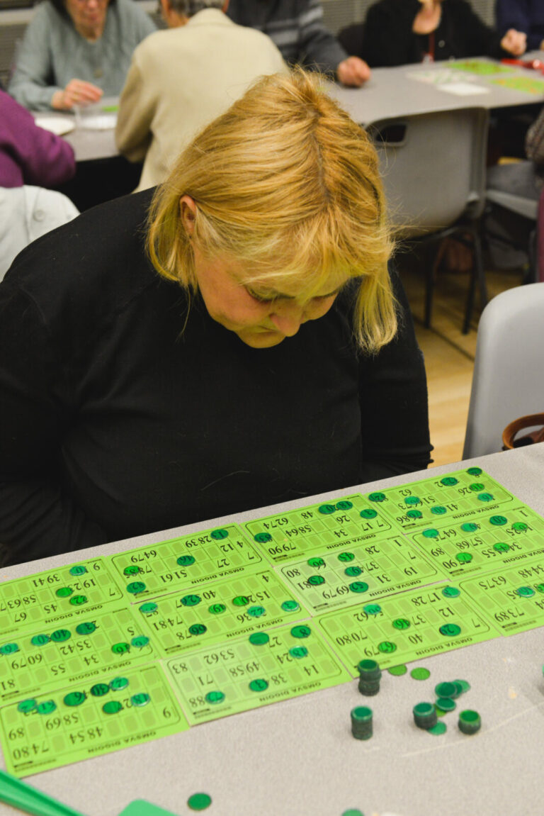 France, Digoin, 2022-03-30. A woman looks at the many bingo tickets laid out in front of her during a game. Photograph b