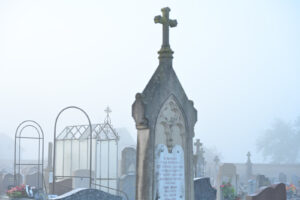 France, Digoin, 2026-10-16. A grave adorned with a glass headstone among the traditional stone headstones in a cemetery,