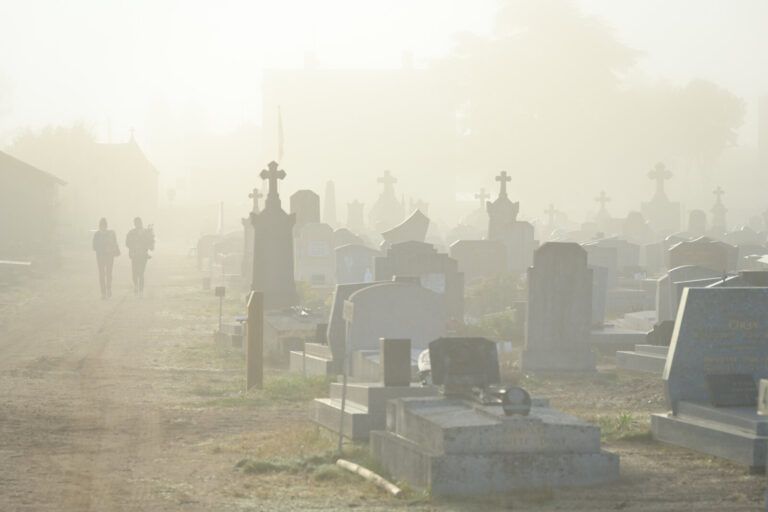 France, Digoin, 2026-10-16. Two small figures are walking down a cemetery path in a misty atmosphere at sunrise. Photogr
